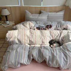 a cat sleeping on top of a bed in a room with pink sheets and pillows