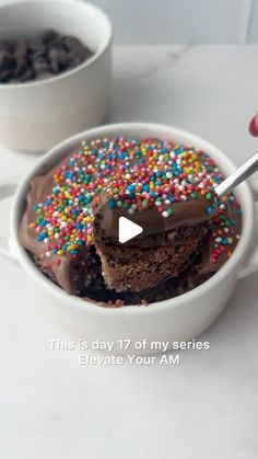 someone is holding a spoon over a bowl of ice cream with chocolate and sprinkles