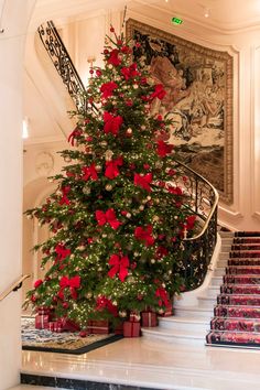 a decorated christmas tree in the middle of a staircase with red poinsettis