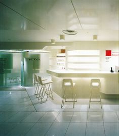 an empty room with several chairs and tables in front of the counter, all white