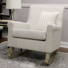 a white chair sitting on top of a rug next to a lamp