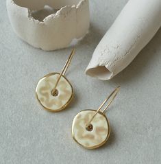 A pair of beautiful handmade elegant ceramic earrings in off-white and gold. Modern organic shape. Comfortable and lightweight to wear. DIMENSIONS & MATERIALS Ceramic piece: 1.5cm, total drop length 3cm white earthenware clay, food safe glaze, gold lustre. Gold plated stainless steel ear wire. PRESENTED in a brown gift box. CONDITION OF THE PRODUCTS Because all our pieces are handcrafted, there may be minor variations form item to item. White Hoop Earrings, Ceramic Accessory, Ceramic Earrings, Jewellery Gifts, Ceramic Earring, Clay Food, Handmade Jewelry Gift, Earrings Small, Ceramic Jewelry