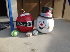 two painted pumpkins sitting on the ground next to each other, one with a hat and bow tie