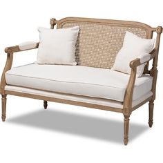 a white couch with two pillows on top of it and some wood frame around the armrests