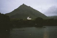 a white house sitting on top of a mountain next to a body of water with mountains in the background