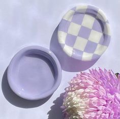 two purple and white plates sitting next to a flower