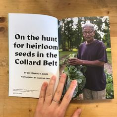 an older man is holding up a book on the table with his hand in front of it