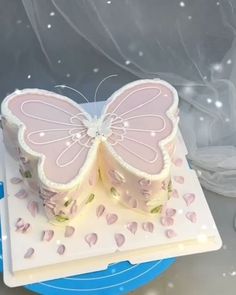 a pink butterfly shaped cake sitting on top of a white plate with frosting around it