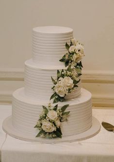 a three tiered white wedding cake with flowers on top