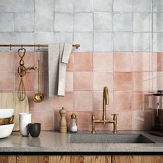 a kitchen with pink tiles and gold faucets on the counter top next to a sink