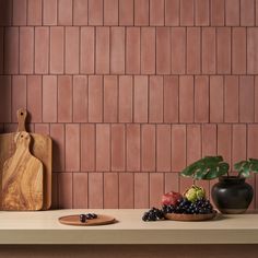 a wooden cutting board sitting on top of a counter next to a bowl of fruit