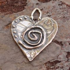 Spiral Adorned Heart!  These are light-weight yet very durable.  The backside is smooth. Carl Jung, the famous psychiatrist, said that the spiral is an archetypal symbol that represents cosmic force.  Some consider the spiral a symbol of the spiritual journey. Also considered to represent the evolutionary process of learning and growing.  The 7 dots are symbolic!  It's the perfect number and symbol of  divine abundance. -Size 20mm x 20mm -Loop is about 5x3mm -Thickness at center is 2mm -Sterling Silver -Option for Jump Ring: 16 gauge sterling silver (5mm inside diameter) You will need a jump ring to hang nicely on a necklace or to attach to a bracelet. If you are knotting on leather for a necklace then you don't need one. The round jump ring is a standard 16 gauge shown in last photo. Plea Sacred Spiral, Pmc Jewelry, Silversmithing Jewelry, Learning And Growing, Ormond Beach, Metal Clay Jewelry, Precious Metal Clay, Carl Jung, Beads Online