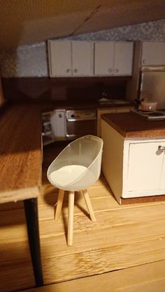 a miniature kitchen with wooden floors and white cabinets in the background is a counter top