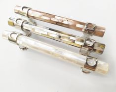 three different types of glass tubes on a white surface with metal rings around the ends