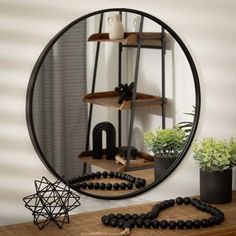 a round mirror sitting on top of a wooden table next to a potted plant