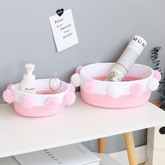 two pink baskets with pom - poms are sitting on a table