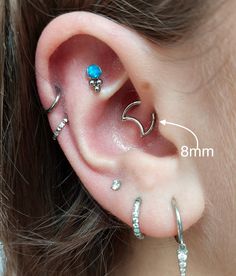 an ear with three different piercings attached to it's sides and two smaller ones behind the ear