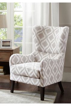 a living room with a white chair and a lamp on the side table in front of a window