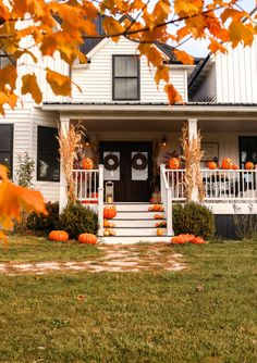 a white house with pumpkins on the front porch