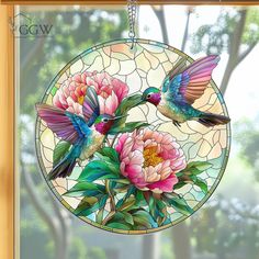 a stained glass window with two hummingbirds and pink flowers on the outside, hanging from a chain