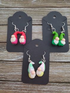 three pairs of earrings with different designs on them sitting on top of a wooden table