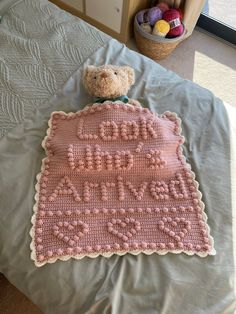 a crocheted teddy bear laying on top of a bed next to a blanket