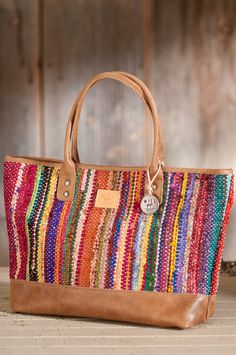 a multicolored handbag sitting on top of a wooden table next to a wall