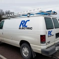 a white van parked in a parking lot next to a blue and white sign that says rc electric