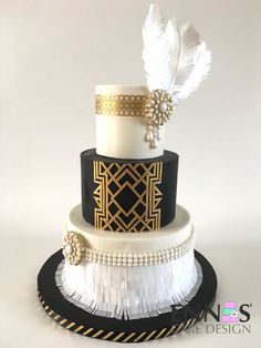 a three tiered black and white wedding cake with feathers on it's side