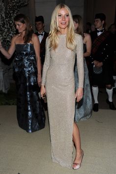 a woman in a long dress standing next to other people at a formal event and posing for the camera