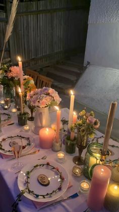 a table set with candles, plates and flowers