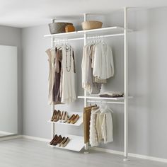 a white closet with clothes and shoes hanging on the wall next to an open door