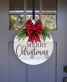 a merry christmas door hanger on the side of a gray door with a red and black plaid bow