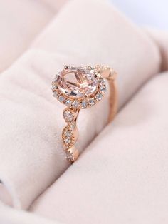 a pink diamond ring sitting on top of a white cloth