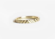 a yellow gold wedding ring with wavy lines on the outside, set against a white background