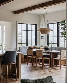 a living room filled with furniture next to large windows and a wooden table surrounded by chairs