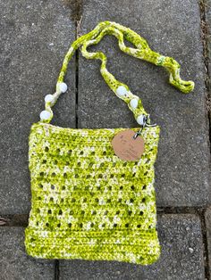 a crocheted purse with a tag attached to it on the ground next to a sidewalk