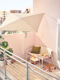 an umbrella is on the balcony next to a chair with a pillow and other items