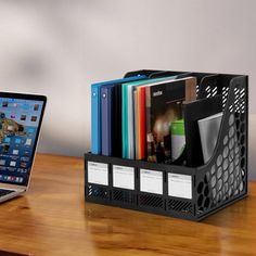 an open laptop computer sitting on top of a wooden desk next to a stack of folders