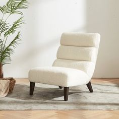 a white chair sitting on top of a wooden floor next to a potted plant