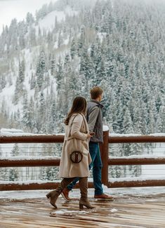 a man and woman standing next to each other on top of a snow covered slope