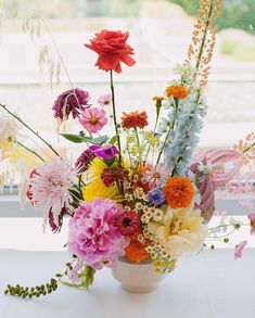 a vase filled with lots of different colored flowers