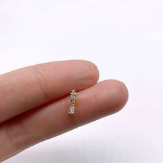 a person's hand holding a tiny gold ring with three small diamonds on it