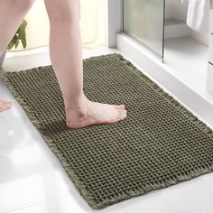 a person standing on a bathroom rug in front of a shower