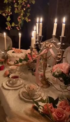 a table topped with lots of plates covered in cake next to lit candles and flowers