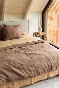 the bed is made with brown linens and pillows