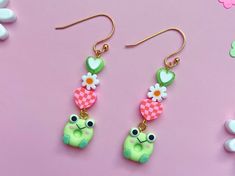 Check out these sweet little frog friend earrings! Perfect for spring or summer, these charming accessories feature adorable clay frog charms, daisy beads, and clay pink checkerboard hearts. A green resin heart charm tops the stack and is attached to a gold fish hook. These hang about 2.5 inches down and are the perfect compliment to a sundress. These would also make a sweet just-because or birthday gift for your cottagecore, life sim playing bestie! Handmade by me, Nat, from Offkilter Co.  Meas Keroppi Cuff Earrings, Cottagecore Kawaii, Clay Frog, Cottagecore Life, Pink Checkerboard, Earrings Cottagecore, Daisy Beads, Frog Earrings, Kawaii Jewelry