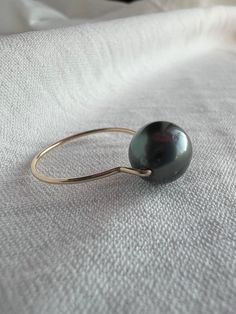 Discover the understated elegance of this size 5 Dark Grey Tahitian Pearl Ring.* Featuring a premium 8-9mm Tahitian pearl at its center. The unique setting features the pearl perched atop gold-filled wire, creating an illusion of floating elegance. This minimalistic design highlights the pearl's iridescence, making the ring versatile for both casual and formal occasions. Crafted for durability and comfort, the gold-filled wire ensures a lasting, tarnish-resistant finish. Ideal for a minimalist statement or a stylish stacked ensemble, this ring is a timeless addition to any collection, offering a touch of class and refined beauty. Handcrafted in our Texas studio with the highest quality materials.  *The item shown in the picture is available for immediate shipment. *For questions about diff Yellow Gold Tahitian Pearl Ring, Yellow Gold Tahitian Pearl Ring Gift, Classic Tahitian Pearl Ring For Wedding, Gift Yellow Gold Tahitian Pearl Ring, Gift Tahitian Pearl Ring In Yellow Gold, Classic Tahitian Pearl Wedding Ring, Classic Tahitian Pearl Rings As Gift, Tahitian Pearl Charm Jewelry, Elegant Tahitian Pearl Ring Gift