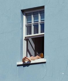 a woman laying on the window sill reading a book