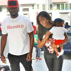 a man and woman walking down the street with a small child in their arms,